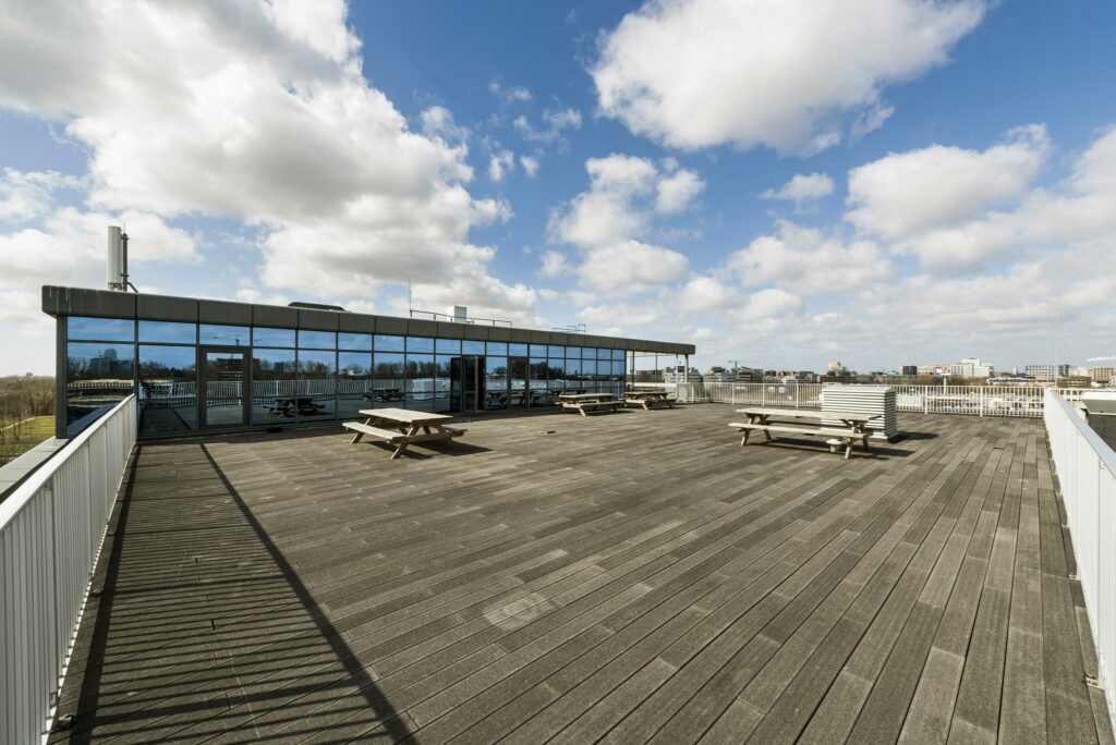 Ruim dakterras met houten vlonders, picknicktafels en uitzicht op de skyline aan de Anthony Fokkerweg.